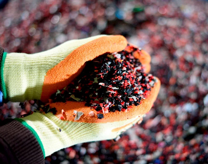 A person's hands holding a pile of red and black gravel.