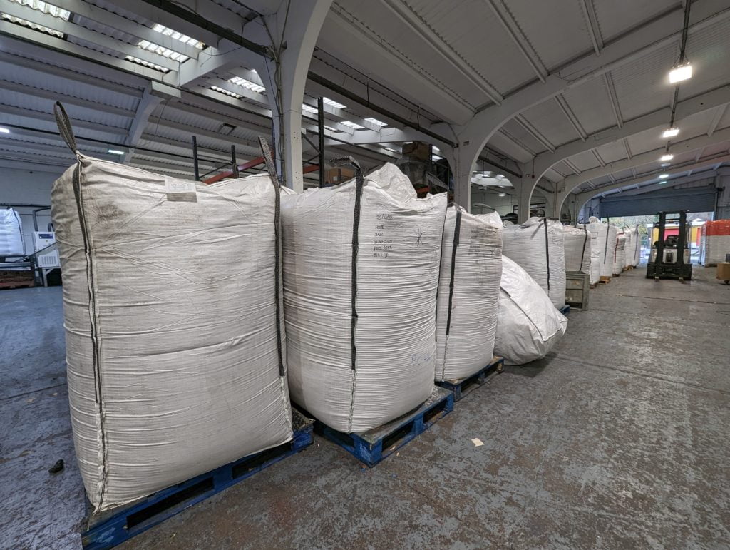 White sacks in a warehouse filled with pallets.