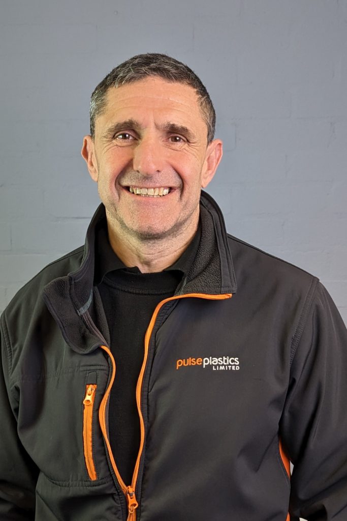 A man in a black and orange jacket smiling.