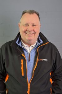A man in an orange and black jacket smiling.